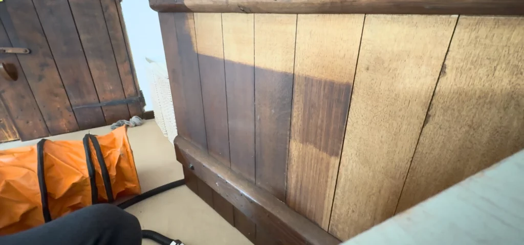 Dark varnished oak panelling part way through laser cleaning, with stripped and unstripped sections side by side